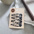 Dettaglio di set 4 mollette per capelli con motivo marmorizzato nero e bianco su carta - Macchie Bianche e Nere