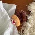 Detail eines Wollfilz-Haargummis mit braunem Spiralband auf einem Holztisch - Hotdog-Form / Rot