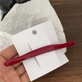 Detail van een gebogen donkerrode schildpad haarklem op een witte displaykaart - Rood