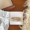 Gros plan de barrettes en acétate beige à motif marbré sur un fond en bois sombre - Barrettes ovales / Couleur Kaki