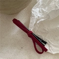 Macro shot of dark red suede bow hair clip with textured fabric and black metal duckbill grip - Red
