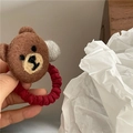 Detailansicht eines braunen Wollfilz-Bären-Haargummis mit grauem Pompon und rotem Band - Brauner Bär mit Grauem Ball
