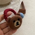 Detail eines süßen Filzbären-Haargummis mit rotem Gummiband und blauem Bommel-Accessoire - Brauner Bär mit Blauem Ball