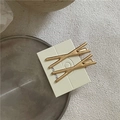 Dettaglio di fermagli per capelli dorati a forma di X in lega spazzolata su espositore - Stile Oro a X