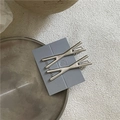 Dettaglio di fermagli per capelli in metallo argento a X con texture spazzolata - Stile Argento a X