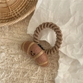 Close-up of wool felt croissant hair tie on beige fabric with a creative design - Croissant / Beige