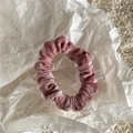 Detail of soft dusty pink velvet scrunchie placed on white crumpled paper - Pink
