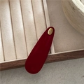 Nahaufnahme der roten Wildleder-Haarspange mit goldener 'Hand made' Metallplakette - Rot