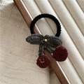 Close-up of knit cherry bow hair tie with smile embroidery on a jewelry tray - J8.1 Cherry Hair Tie