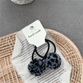 Detail view of two fluffy leopard print hair ties on a handmade card with neutral decor - Black Multicolor