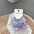 Detail eines handgefertigten hellblauen Haargummis mit bunten Pompons auf Bastelkarte - Rosa Lila Blau