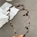 Detail view of wavy leopard print headband with teeth on a minimalist stone background - Transparent Gray Leopard