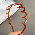 Close-up of stylish amber wavy headband featuring unique black branch-like textures - Transparent Tea Lines