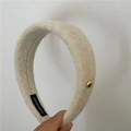 Détail du serre-tête en laine rembourré beige avec étiquette et bouton doré - Blanc Cassé