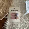 Detailed close-up of pink felt BB hair clips with colorful pompoms on handmade packaging card - White Pom Pom Clips