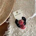 Detail of two handmade elastic hair ties with colorful red pom-poms on a soft textured background - Red Pom Pom Hair Ties