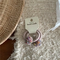 Detail of colorful fuzzy pom pom hair ties on a handmade card over a woven tray - Khaki Pom Pom Hair Ties