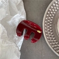 Détail d'une pince à cheveux bordeaux brillante avec une étiquette dorée Hand Made ronde - Bordeaux