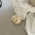 Nahaufnahme einer kleinen ovalen Haarklammer mit beiger Marmortextur aus Acetat-Material - Cremeweiß