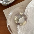 Detail of spiral hair tie with grey-purple marble texture on a decorative glass dish - Gray and White Gradient