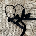 Detail view of two black velvet ribbon bow hair ties on a minimalist textured background - Black