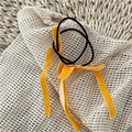 Detail view of a yellow velvet ribbon bow hair tie on a rustic white textured background - Yellow