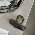 Detail view of a translucent charcoal hair claw clip with golden spring and silver accessory - Transparent Grey