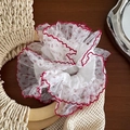 Détail d'un chouchou en organza blanc avec broderie florale rouge et bordure en dentelle - Bord Rouge