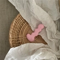 Close-up of a glossy pink caterpillar wave hair clip on a textured woven mat - Light Pink