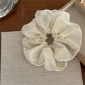 Détail d'un chouchou élégant en organza blanc cassé avec coutures fines sur fond rustique - Scrunchie en Maille
