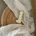 Detailed close-up of a creamy white wavy resin hairpin on a textured woven tray - Off White
