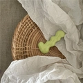 Close-up of a light green wavy caterpillar hair clip on a natural woven rattan tray - Light Green