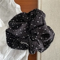 Dettaglio dell'elastico per capelli nero a fiori con trama a pieghe su sfondo caldo - Stile a pois / Grande / Nero