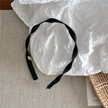 Diadema minimalista de cinta negra con detalle metálico dorado en fondo texturizado - Negro