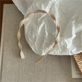 Detalle de la fina textura y los elegantes pliegues ondulados de la diadema de cinta beige - Caqui