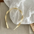 Primer plano de una diadema fina amarillo pálido con textura acanalada sobre fondo de lino - Beige