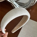 Close-up of beige fabric sponge headband showing its natural woven texture and soft suede lining - Off White
