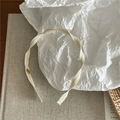 Detalle de diadema de tela acanalada crema con placa redonda dorada de logotipo - Blanco