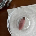 Dettaglio di un fermaglio per capelli rosa opaco su un piatto di vetro e lino fine - Marrone