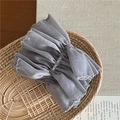 Dettaglio dell'elastico per capelli in mesh grigio con ricamo in un cesto di paglia - Scrunchie in Mesh / Grigio