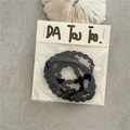 Primer plano de una goma de pelo en espiral negra sobre una tarjeta de marca blanca - Negro