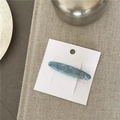 Detalle de horquilla de acetato azul mármol con logotipo dorado en tarjeta blanca - Azul