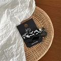 Detail of wavy acetate hair clips in black and marble patterns on display card - Black Marble Pattern