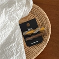 Close-up of wavy acetate hair clips in amber and brown on a black display card - Amber Tortoiseshell