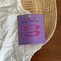Macro detail of two purple cream metal teardrop hair clips on a purple display card - Purple