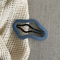 Close-up of wavy blue denim fabric hair clip with black matte metal snap fastener - Dark Blue Cloud