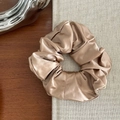 Détail d'un chouchou en satin champagne avec un tissu plissé élégant et un éclat doux - Café Jaune
