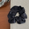 Détail du chouchou en satin noir montrant la texture brillante et les plis élégants - Noir