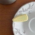 Close-up of a yellow teardrop hair clip with pink stitched edges on a white plate - Yellow Triangle (Duckbill Clip)