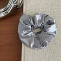 Detailed view of dark silver satin scrunchie on grey fabric book cover in elegant setting - Grey Blue